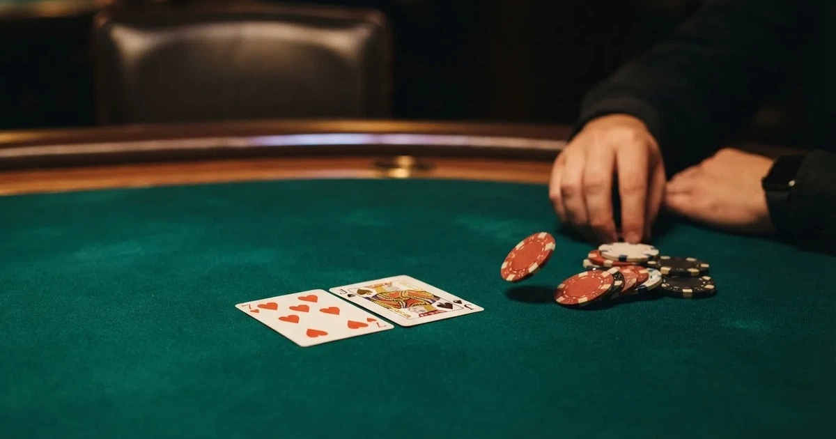 A close-up of a green felt gaming table with cards and chips mid-hand.