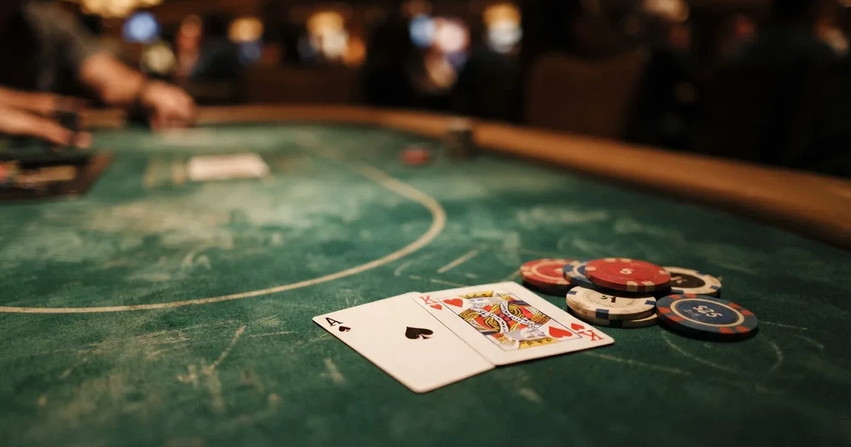 A close-up of a green felt gaming table with cards and chips mid-hand.